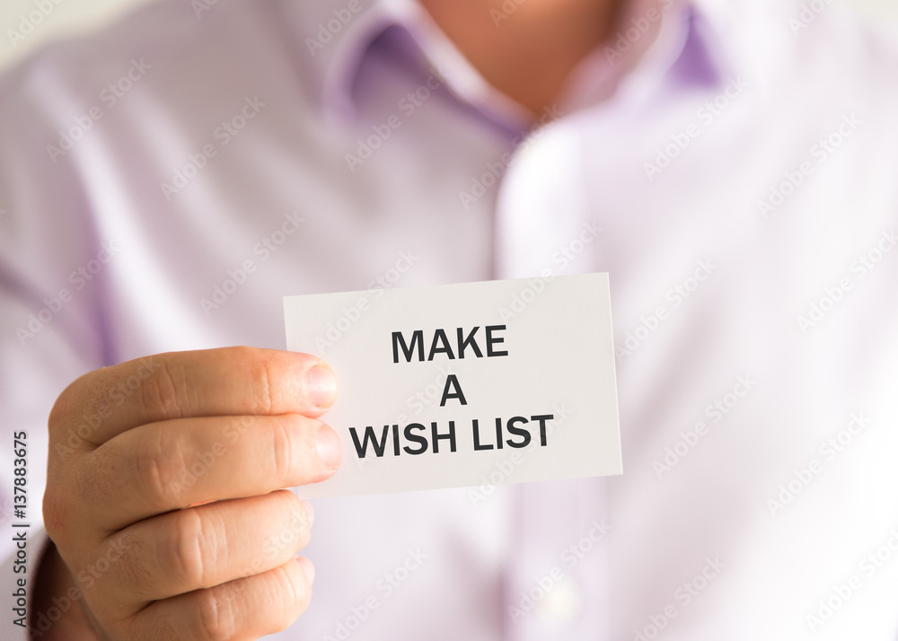 Businessman holding a card with text MAKE A WISH LIST Businessman holding a card with text MAKE A WISH LIST
