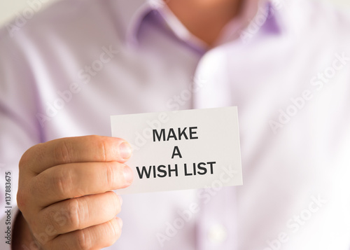 Businessman holding a card with text MAKE A WISH LIST
