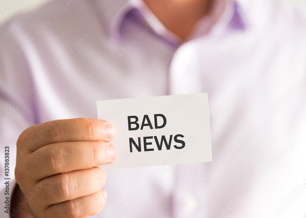 Businessman holding a card with text BAD NEWS Businessman holding a card with text BAD NEWS