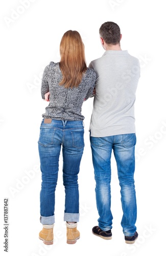 Back view of young embracing couple (man and woman) hug and look