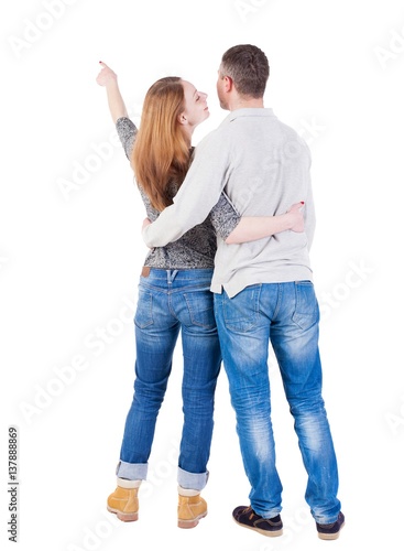 young couple pointing at wal Back view  (woman and man).