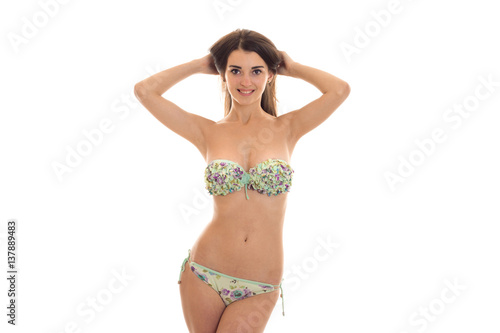 a young attractive girl is standing in a bathing suit and keeps hands head