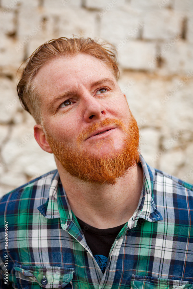 Pensive red haired hipster man with blue plaid shirt Pensive red haired hipster man with blue plaid shirt