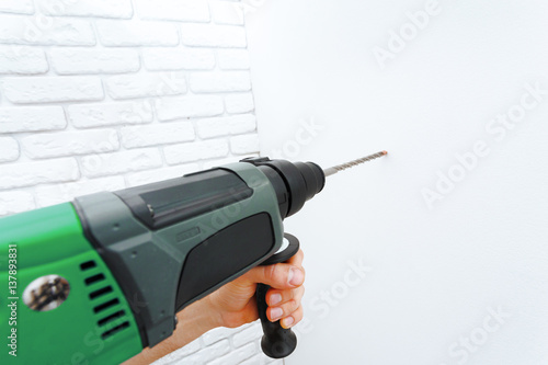 Use hammer drill to drill the wall