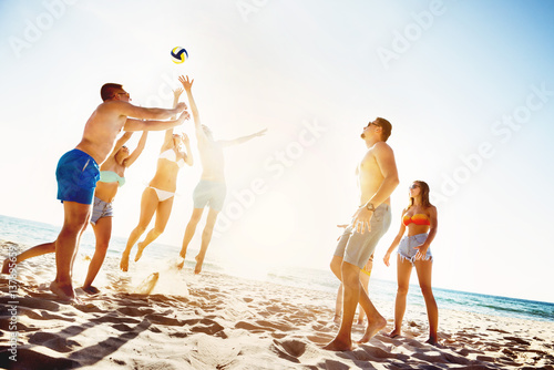 Friends playing beach voleyball sunset time