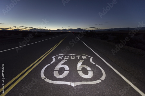 Route 66 pavement sign at night in the Southern California Mojave desert.