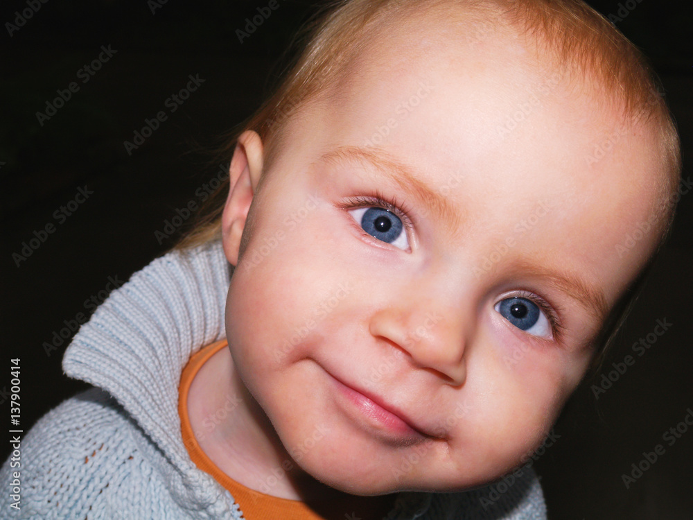 17 Monate altes Kleinkind schaut verschmitzt lächelnd in die Kamera StockFoto Adobe Stock