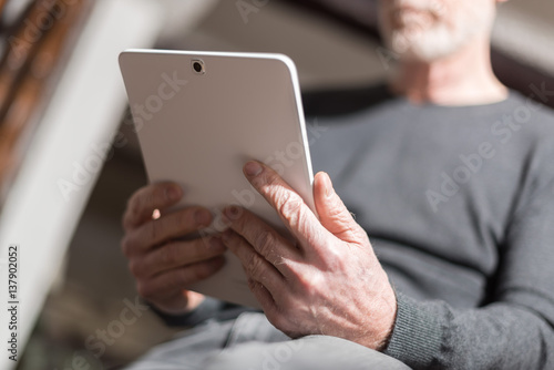 Senior man using his tablet, hard light effect