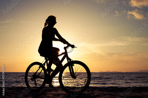 happy woman with bicycle standing on the beach