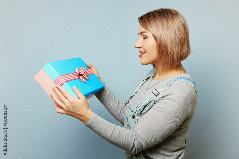 Girl with gift box in her hands on a blue background. Girl with gift box in her hands on a blue background.