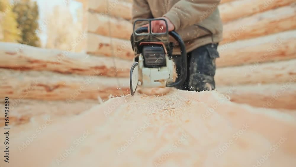 Joiner working chainsaw sawing logs for wooden houses. Canadian angle masonry. Canadian style.