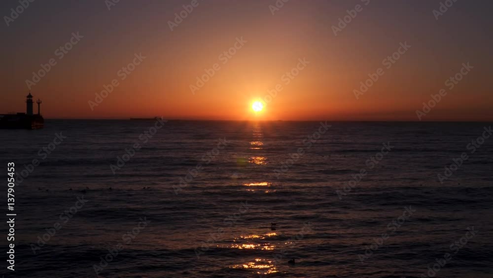 Seascape at dawn. We see the lighthouse and ship. In the sea swim seabirds Seascape at dawn. We see the lighthouse and ship. In the sea swim seabirds