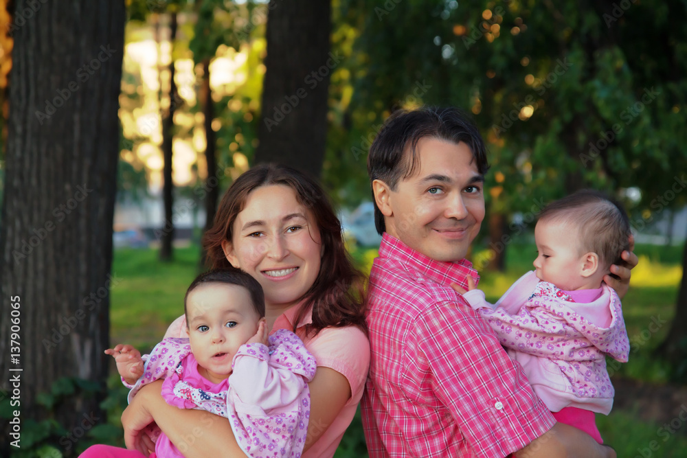 Happy family at the park with father, mother and infant twins baby - sisters Happy family at the park with father, mother and infant twins baby - sisters