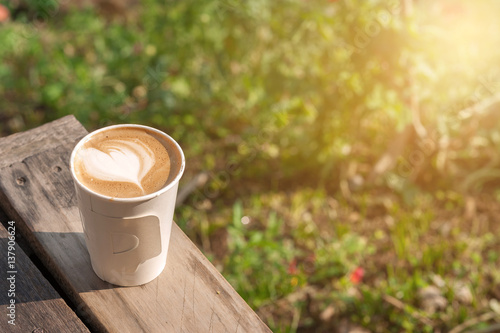 hot coffee in the morning on wood table with blurred garden in background