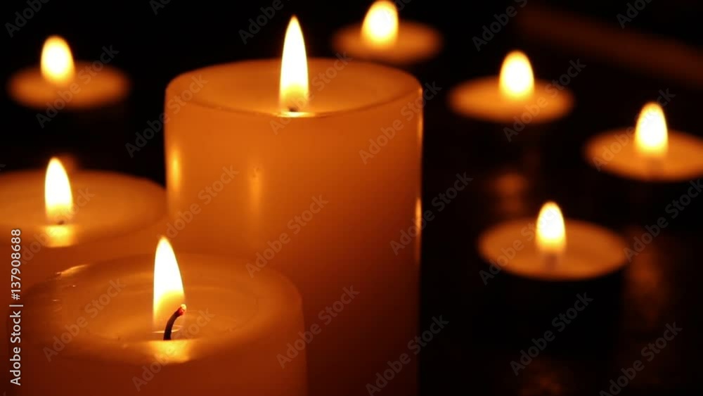 Candles burning at night on a wooden table. Small and big candles and bokeh lights background. Candles burning at night on a wooden table. Small and big candles and bokeh lights background.