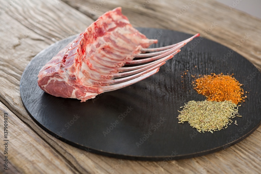 Beef ribs rack and spices on black round tray Beef ribs rack and spices on black round tray