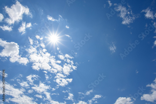 Blue sky with clouds and sun reflection. looking up view
