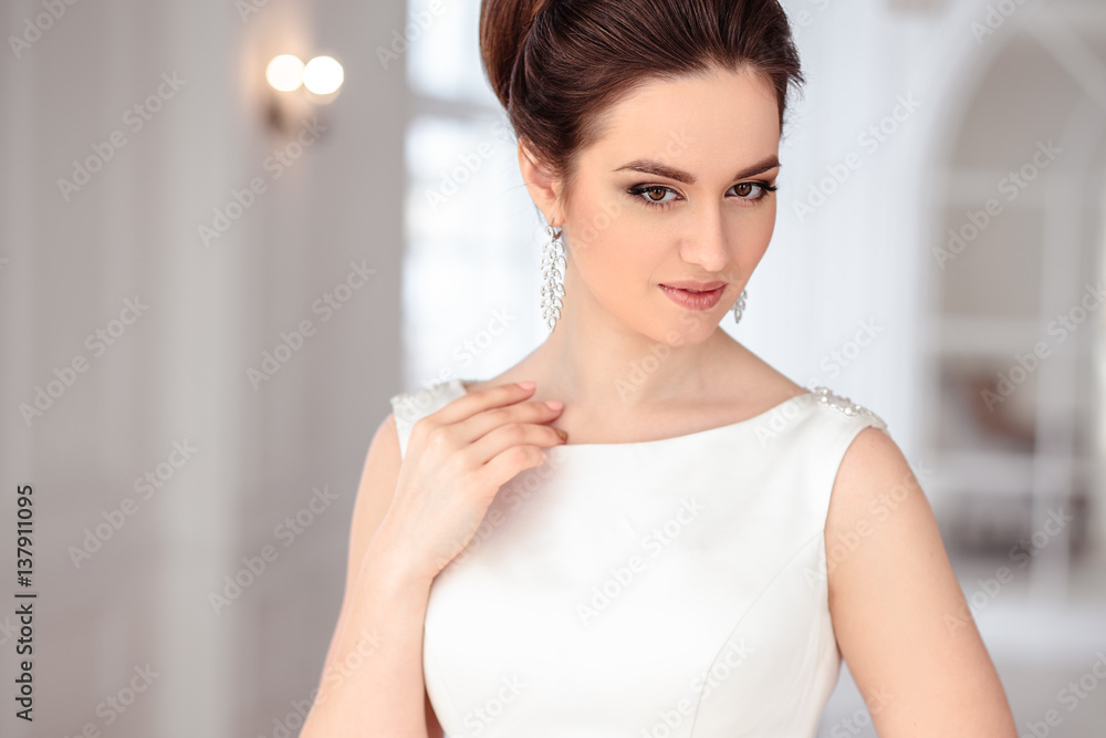 close-up portrait of beautiful brunette bride with elegant hairstyle and makeup wearing long luxury wedding dress