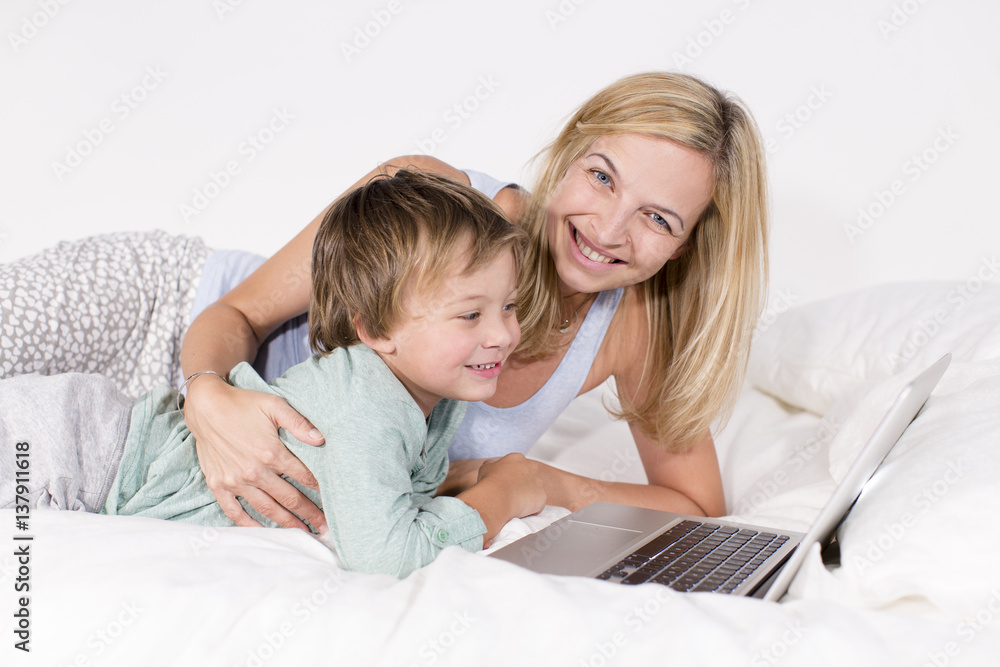 Mutter und Sohn liegen mit Notebook auf einem Bett Mutter und Sohn liegen mit Notebook auf einem Bett