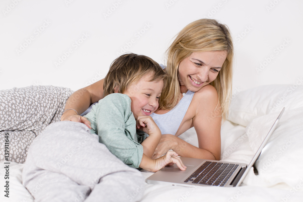 Mutter und Sohn liegen mit Notebook auf einem Bett Mutter und Sohn liegen mit Notebook auf einem Bett