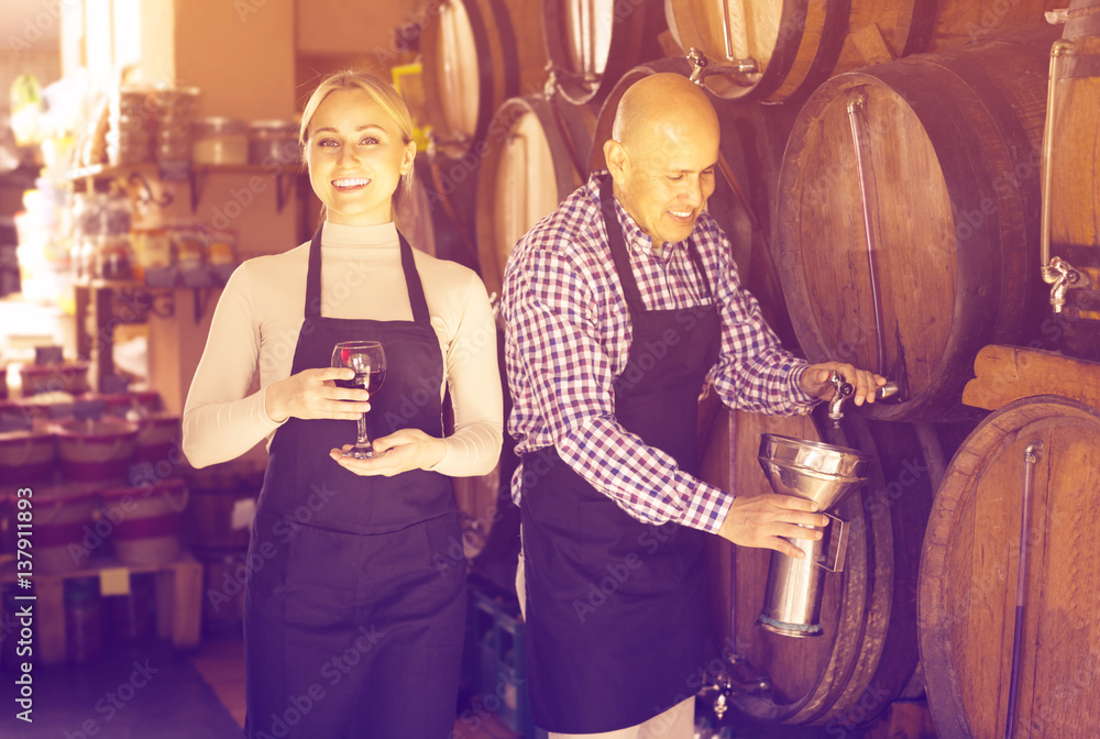 Smiling mature man and young female posing with wine from wood