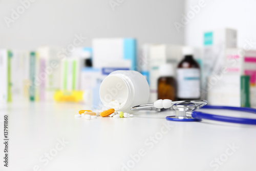 bottle pills and medicine capsule on desk with stethoscope  drugs and tablet boxes  in background