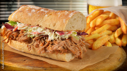 Submarine sandwich pulled pork,coleslaw, fries and a glass of beer.