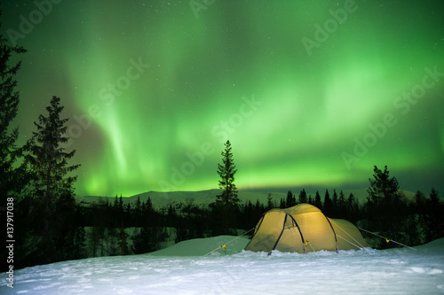 illuminated tent in front of strong aurora display