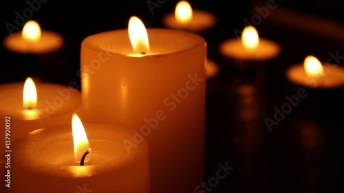 Candles burning at night on a wooden table. Small and big candles and bokeh lights background. 