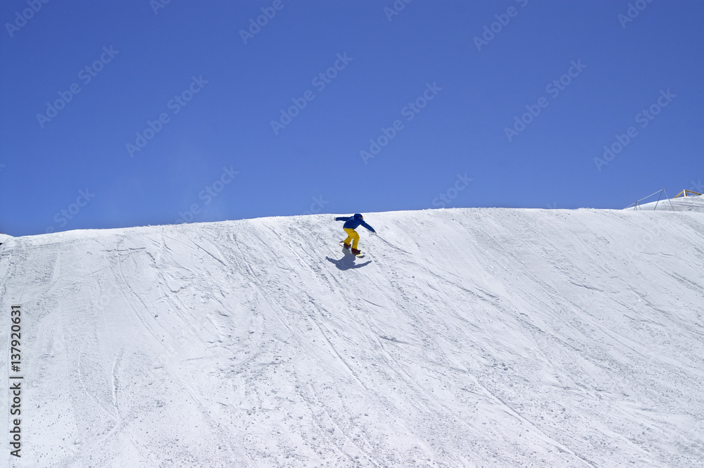 Snowboarder downhill in terrain park on ski resort at sun winter day