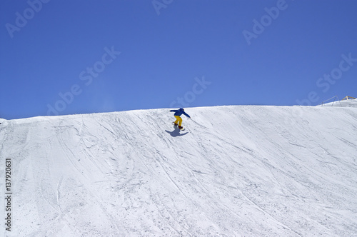 Snowboarder downhill in terrain park on ski resort at sun winter day