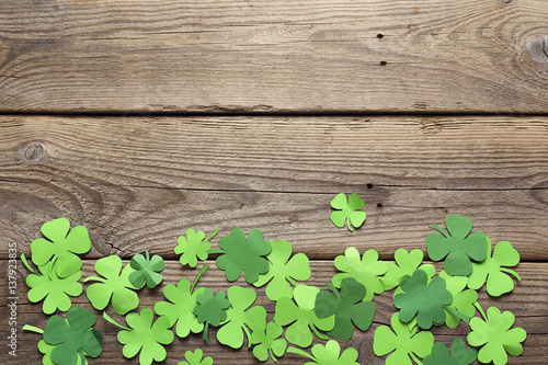 Paper clover leaves on the old wooden background. Lucky shamrock. Space for text.