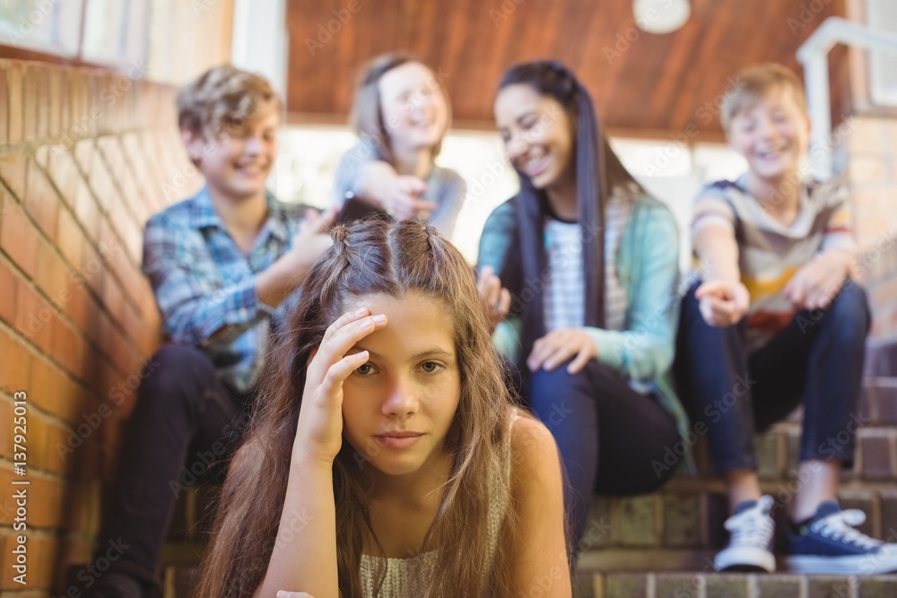 Fototapeta premium School friends bullying a sad girl in school corridor