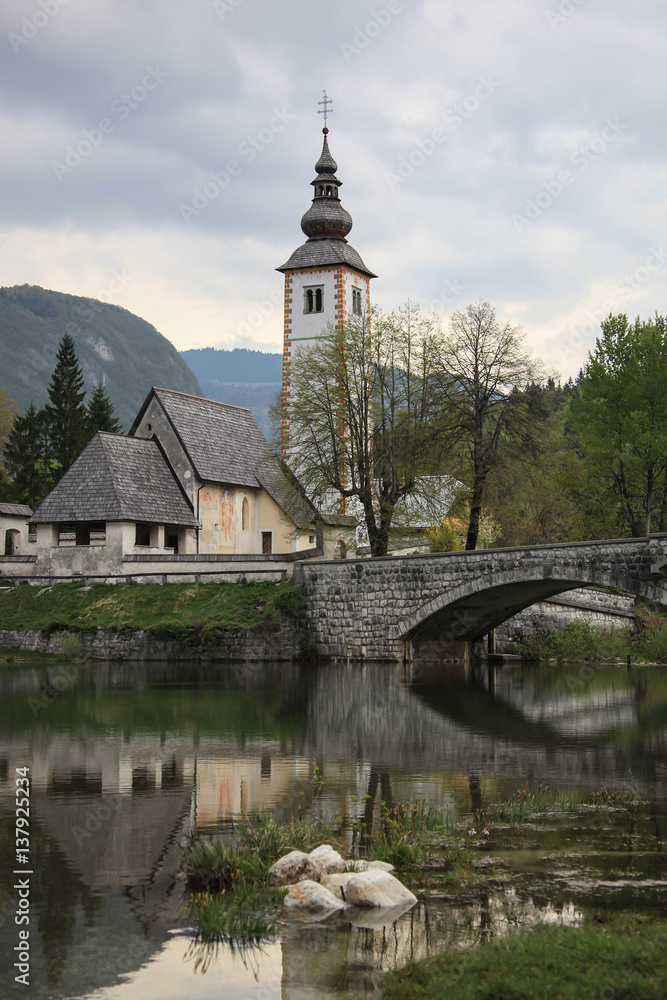 Old stone bridge leads to historical church beside the Lake Bohinj, Slovenia