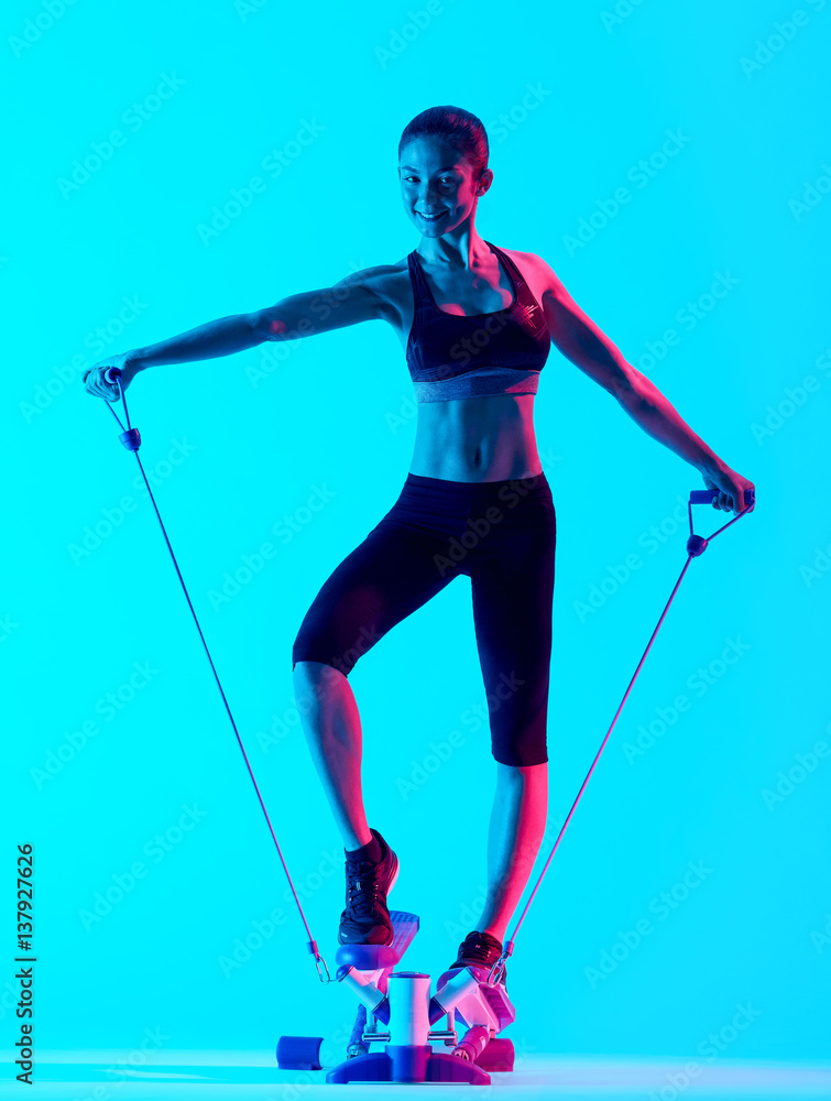one mixed races woman exercsing Stepper fitness exercices isolated on blue blackground one mixed races woman exercsing Stepper fitness exercices isolated on blue blackground