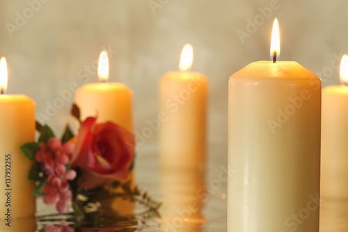 Burning candles with reflection and a pink rose in the background