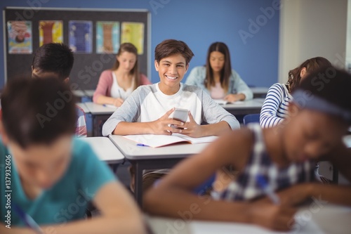 Student holding mobile phone in classroom