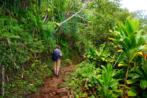 Obraz na plátně Young male tourist hiking on the famous Kalalau trail along Na Pali coast of the