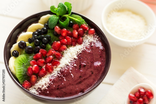 Wallpaper Mural Healthy breakfast: fresh smoothie with kiwi, banana, garnet seeds, blueberry and coconut decorated mint leaves on white wooden table. Selective focus Torontodigital.ca