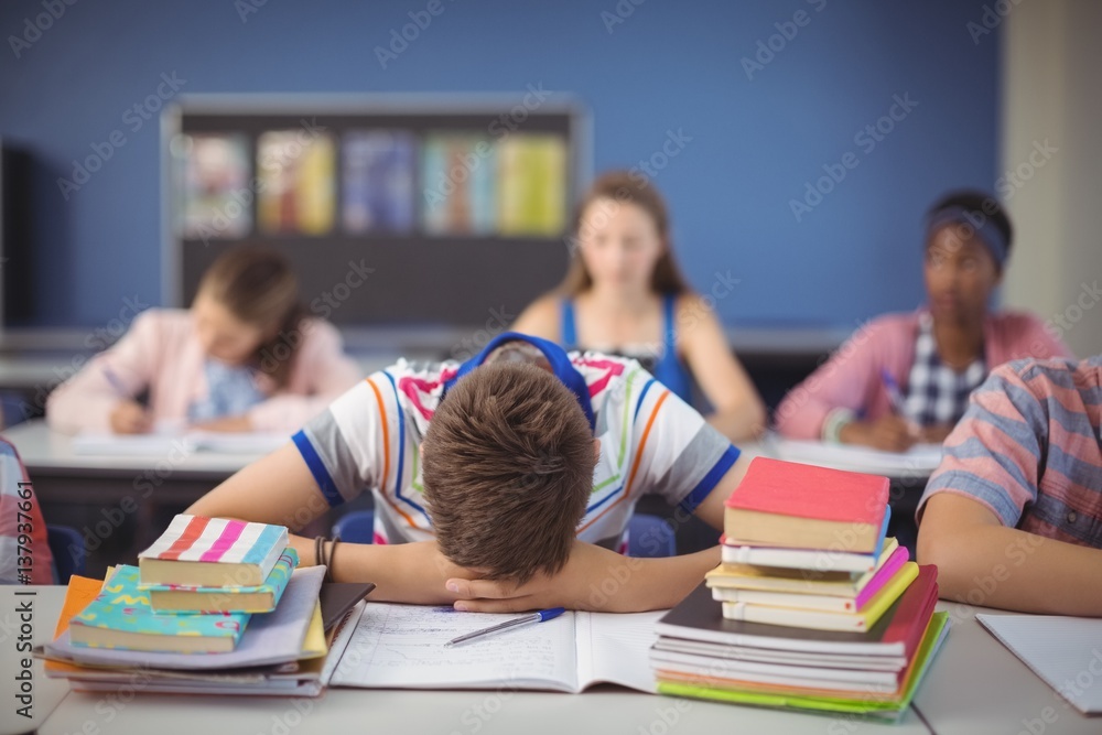 Tired schoolboy sleeping in classroom Tired schoolboy sleeping in classroom