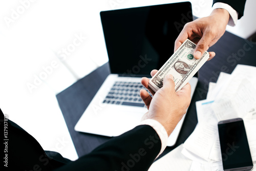 Man offering batch of hundred dollar bills. Hands close up. Venality, bribe, corruption concept. Hand giving money - United States Dollars (or USD). Hand receiving money from businessman,Greeting Deal