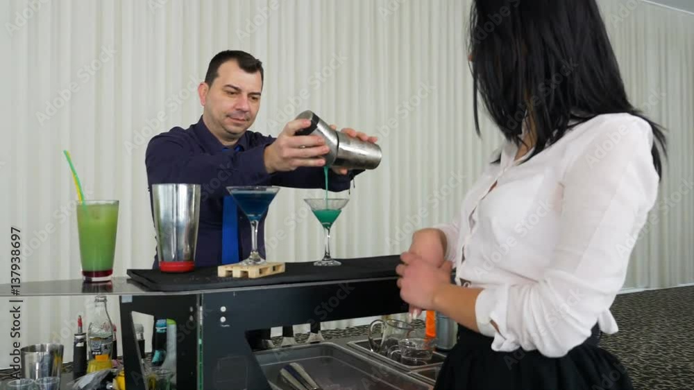 Bartender pouring cocktail from shaker for a girl at the bar Bartender pouring cocktail from shaker for a girl at the bar
