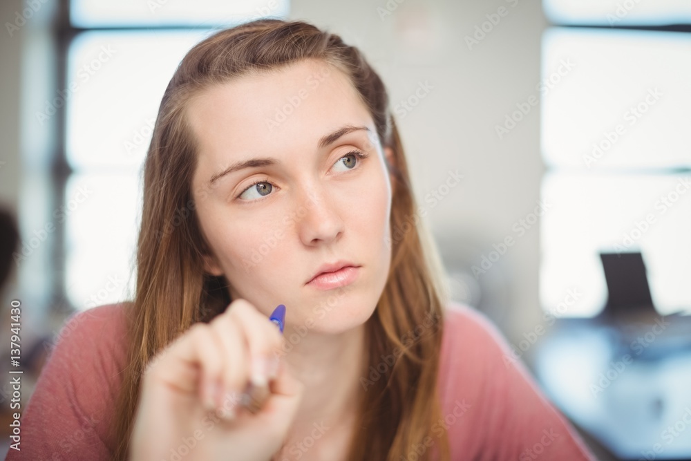 Thoughtful school girl doing homework in classroom Thoughtful school girl doing homework in classroom