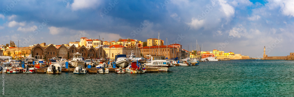 Panorama of Chania Arsenals, the Venetian shipyards, and fishing boats in old harbour of Chania in sunny and cloudy summer morning, Crete, Greece
