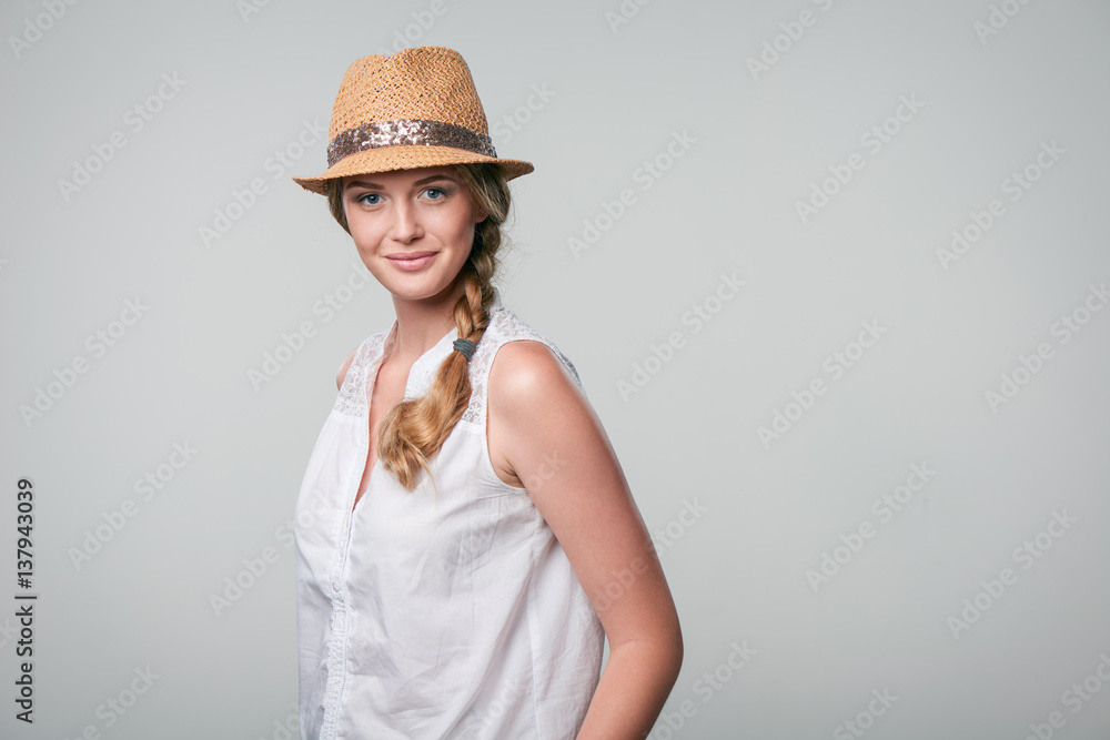 Beautiful smiling woman wearing summer straw fedora hat in carefree stance Beautiful smiling woman wearing summer straw fedora hat in carefree stance