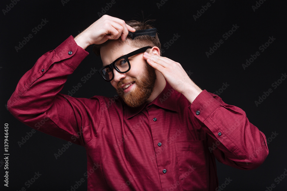 Smiling Male nerd combing his hair Smiling Male nerd combing his hair