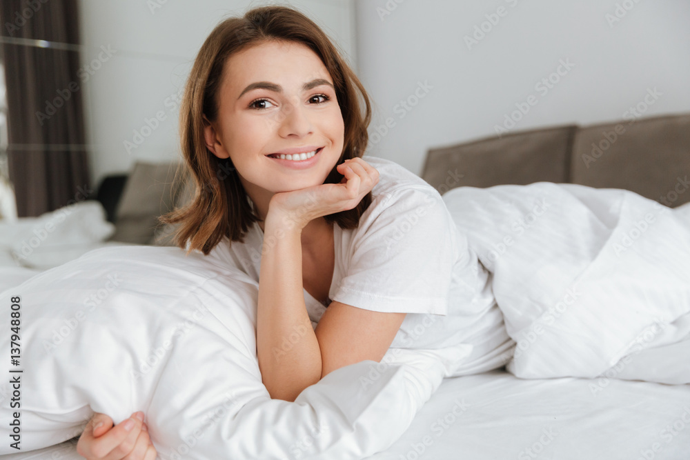 Cheerful woman lies in bed at home indoors. Cheerful woman lies in bed at home indoors.