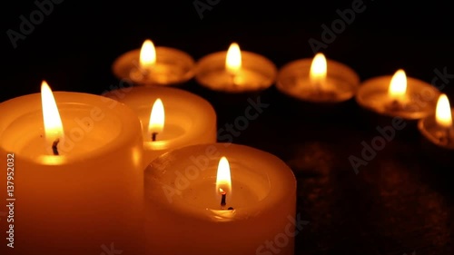Candles burning at night on a wooden table. Small and big candles and bokeh lights background. 