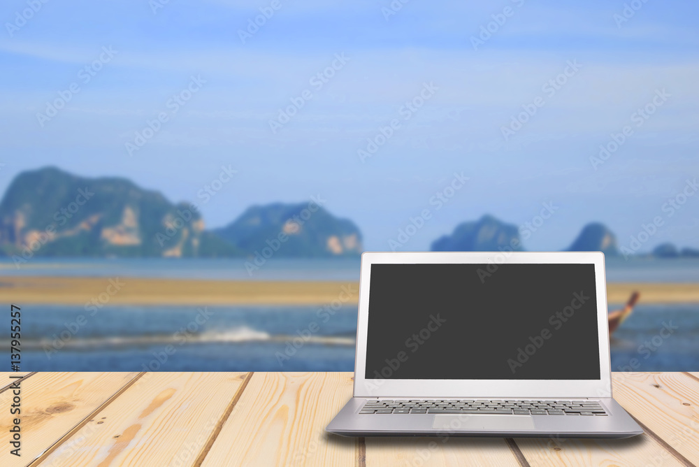 Laptop with blank screen on wooden table with lake and sea