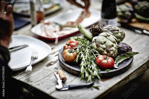 Artichokes, rosemary and tomatoes on a wooden board photo